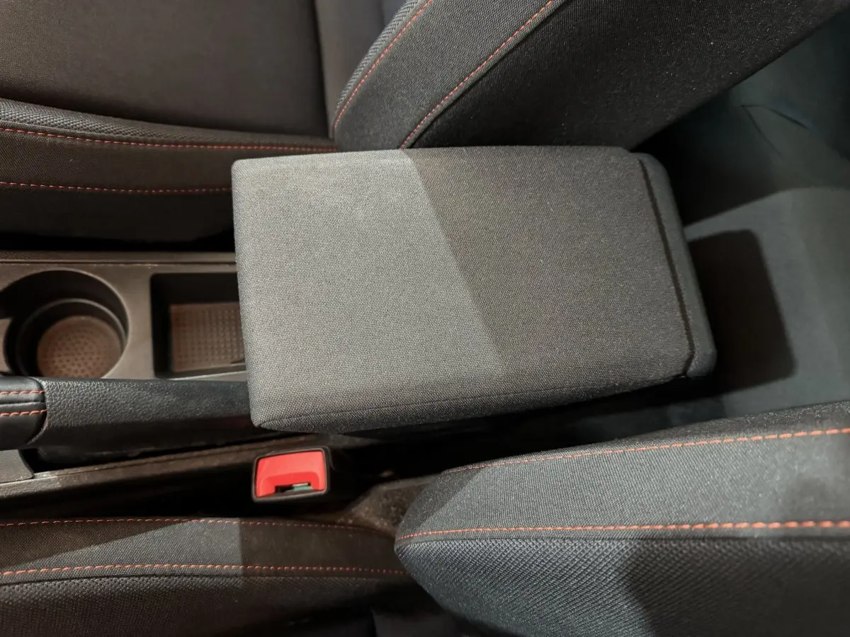 Gros plan sur l'accoudoir central et les sièges noirs avec surpiqûres rouges de la SEAT Ibiza 1.0 TSI 110 FR.