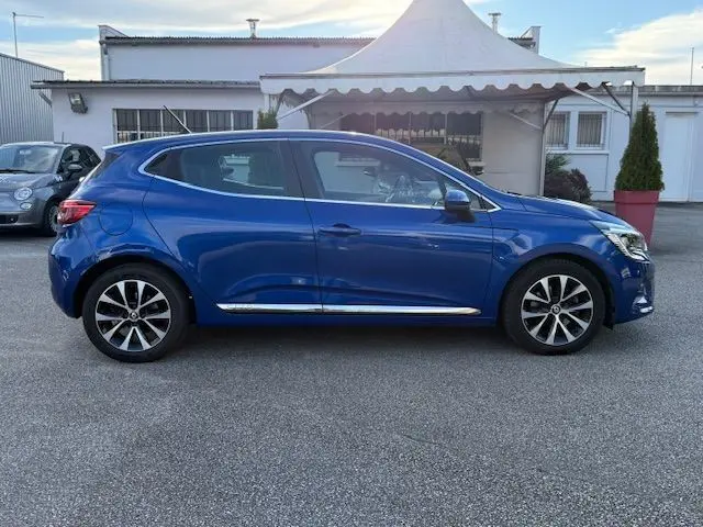 Profil latéral droit d'une Renault Clio V 1.3 TCE 140 Intens bleu Iron, avec jantes alliage et détails chromés sur les bas de porte.