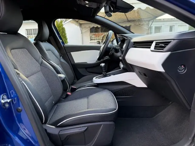 Vue intérieure côté gauche de la Renault Clio V bleu Iron 2022, montrant les sièges avant et le tableau de bord clair.