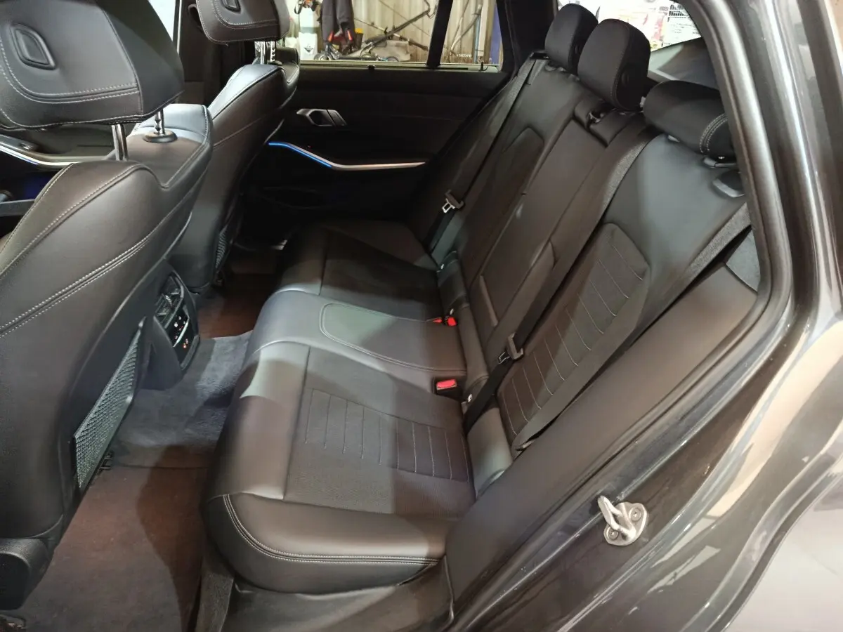 Vue intérieure côté droit des sièges arrière en cuir noir de la BMW Série 3 318d Lounge 2022 avec finitions soignées.