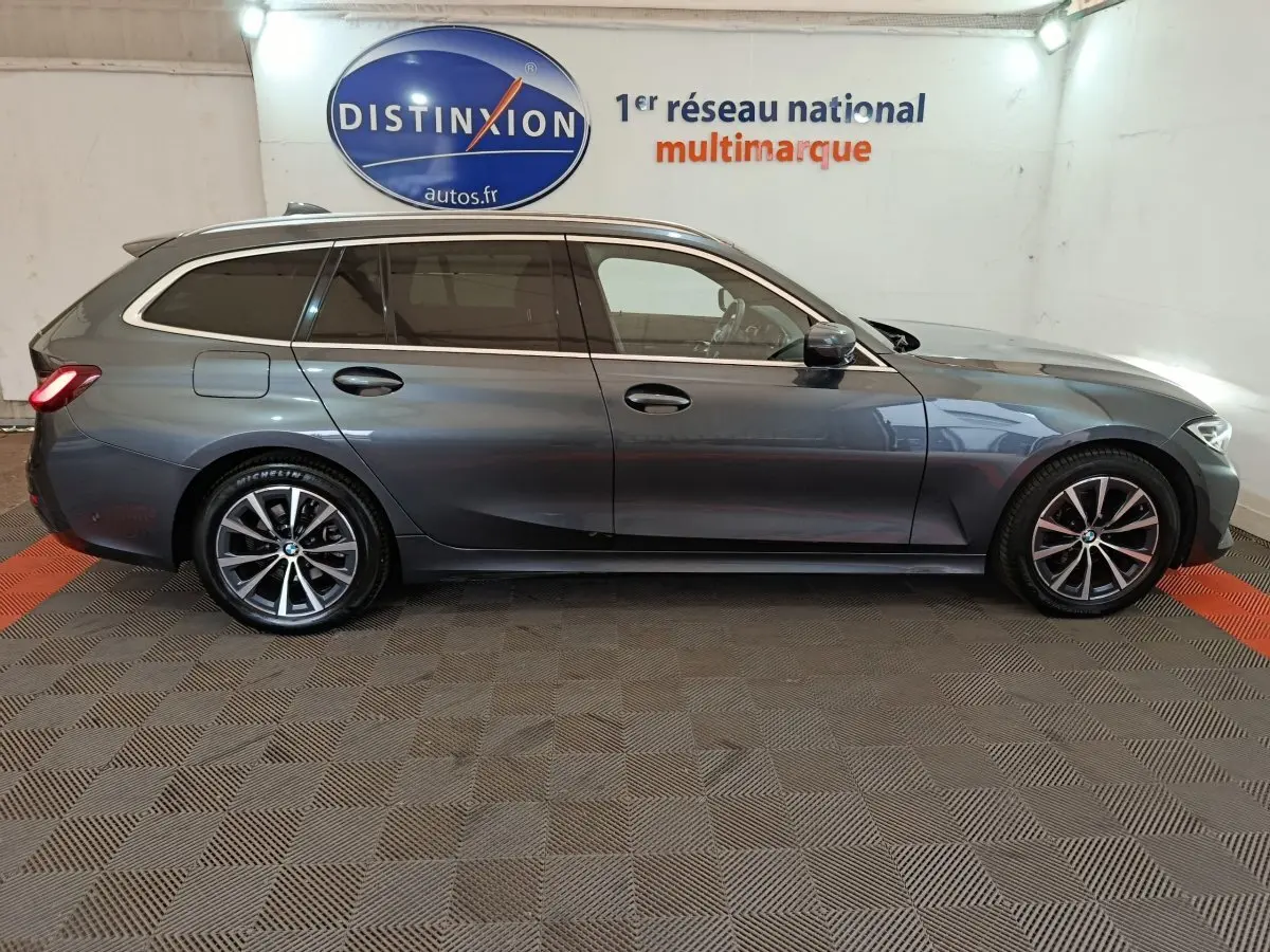 BMW Série 3 318d gris clair vue de profil côté droit en break avec jantes alliage et vitres teintées.