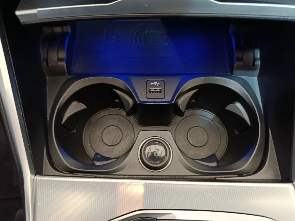 Vue rapprochée de la console centrale noire de la BMW Série 3 318d avec porte-gobelets, prise USB et prise 12V.