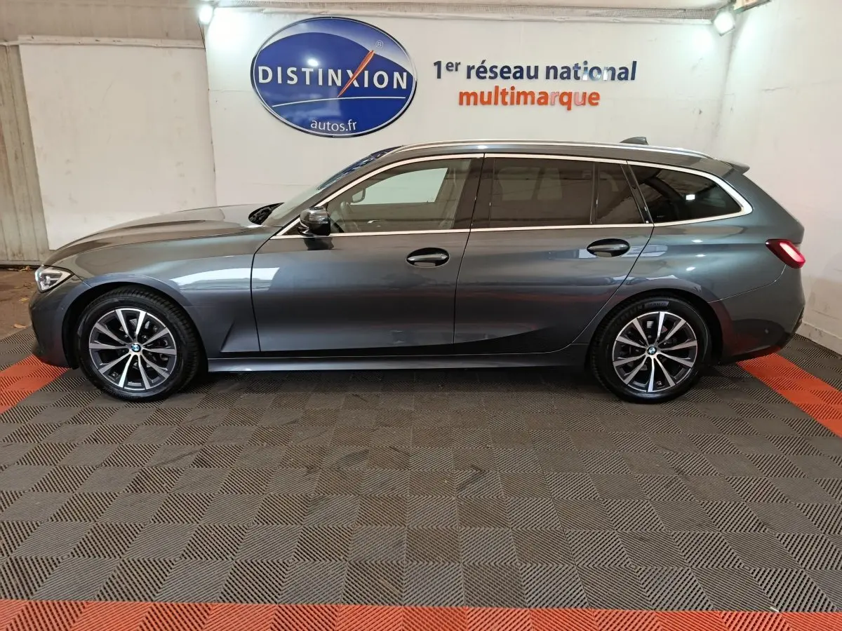 Vue de profil côté gauche d'une BMW Série 3 Touring gris clair avec jantes alliage et rails de toit noirs.