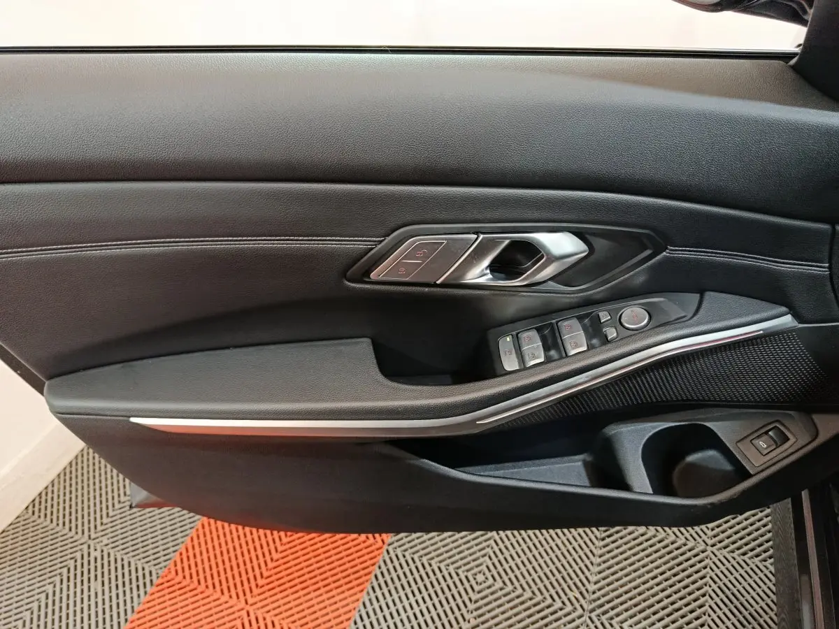 Gros plan sur la porte intérieure côté gauche de la BMW Série 3 318d 2022, avec commandes de vitres et poignée argentée.