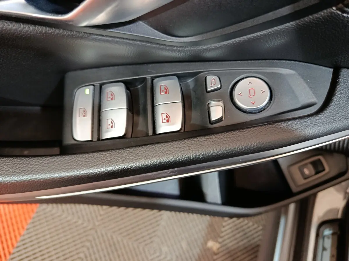 Gros plan sur les commandes des vitres et rétroviseurs côté conducteur d’une BMW Série 3 gris clair 318d Lounge 2022.