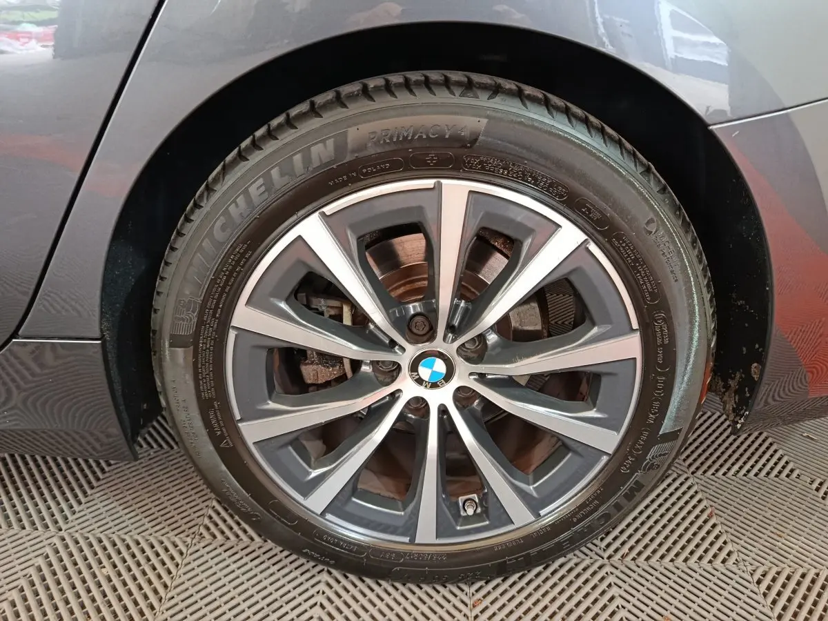 Gros plan sur la roue avant droite d'une BMW Série 3 gris clair, jante alliage à multiples branches.