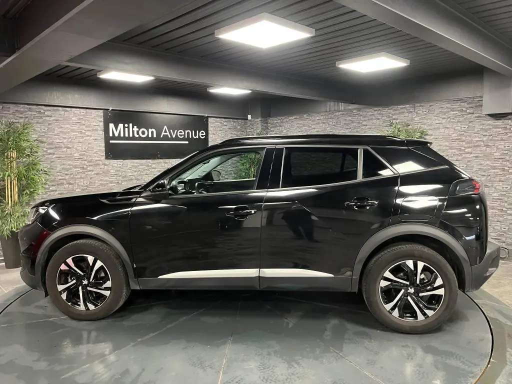 Peugeot 2008 noir perla nacré vue de profil côté gauche, jantes alliage 17'' bi-tons et barres de toit noires.