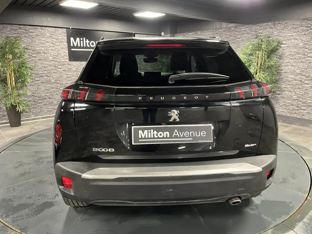 Vue arrière d'un Peugeot 2008 noir Perla Nera avec feux arrière à LED en forme de griffes et becquet couleur carrosserie.