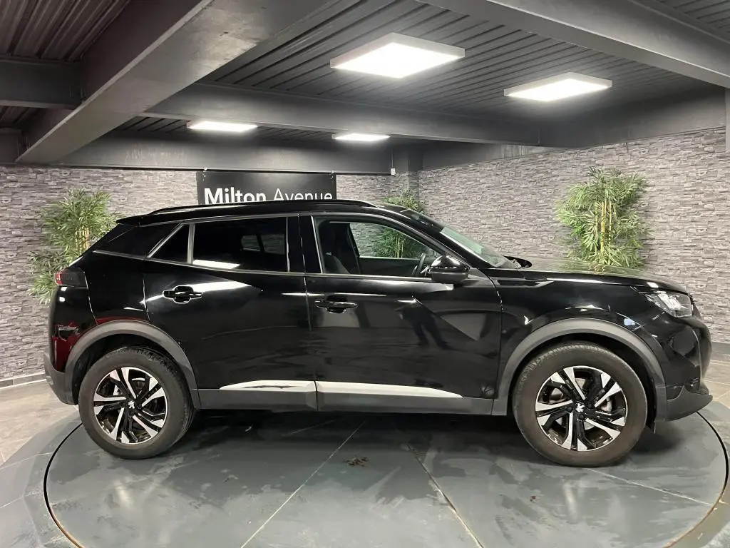 Peugeot 2008 noir perla nacré vue de profil côté gauche, jantes alliage bi-ton et barres de toit noires.