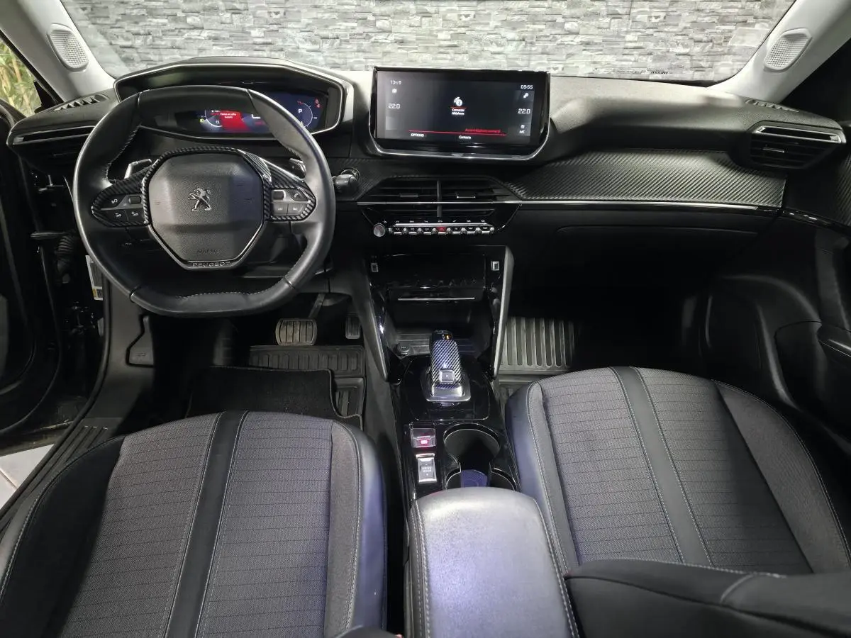 Vue intérieure avant du Peugeot 2008 2021 noir, planche de bord carbone et volant compact cuir avec commandes intégrées.