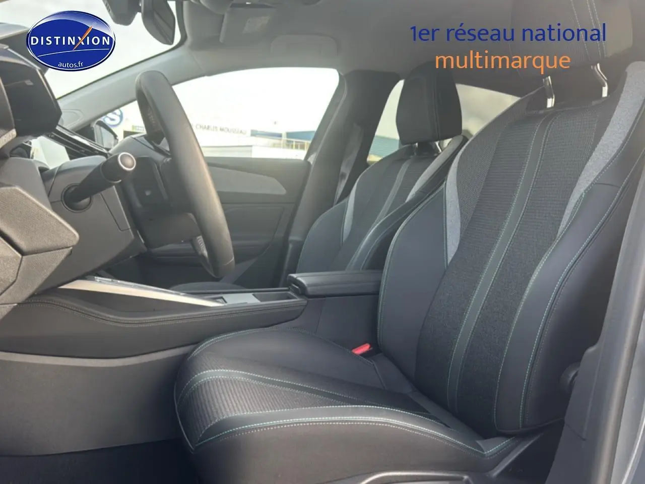 Vue intérieure côté conducteur de la Peugeot 308 2024 avec sièges tissu et cuir noirs et accoudoir central.