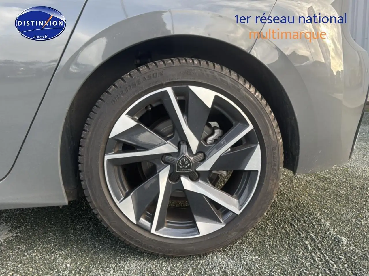 Gros plan sur la roue arrière droite d'une Peugeot 308 gris sélénite avec jante alu au design moderne.