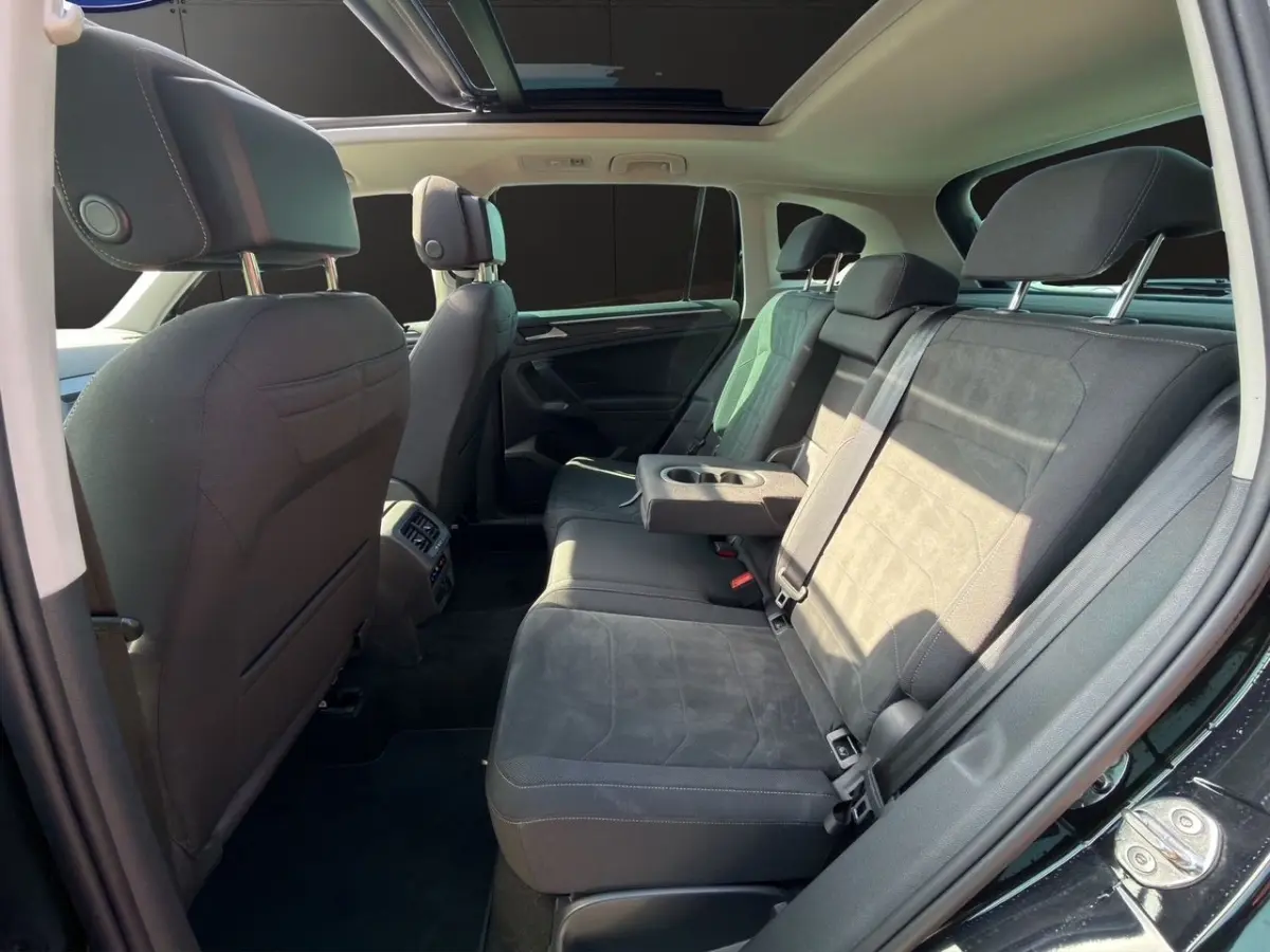 Vue intérieure arrière côté droit du Volkswagen Tiguan noir 2022 avec banquette tissu et accoudoir central rabattable.