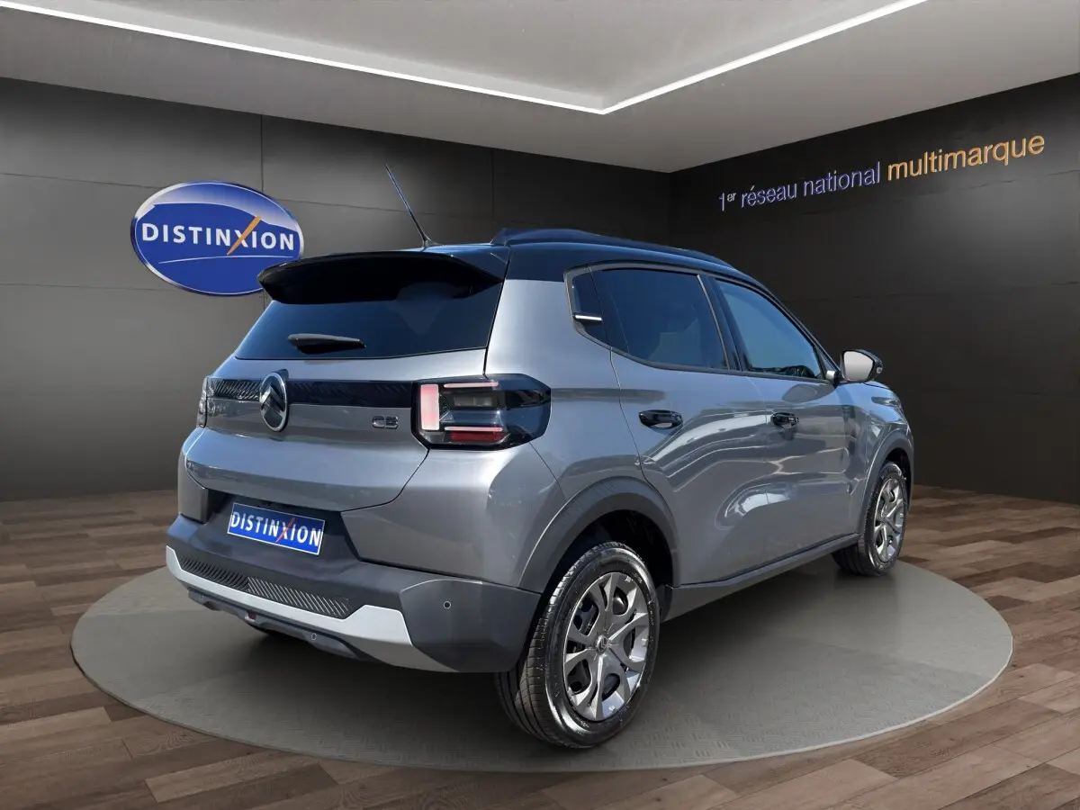 Vue 3/4 arrière droite d'une Citroën C3 2025 gris foncé bi-ton avec toit noir et jantes alliage distinctives.