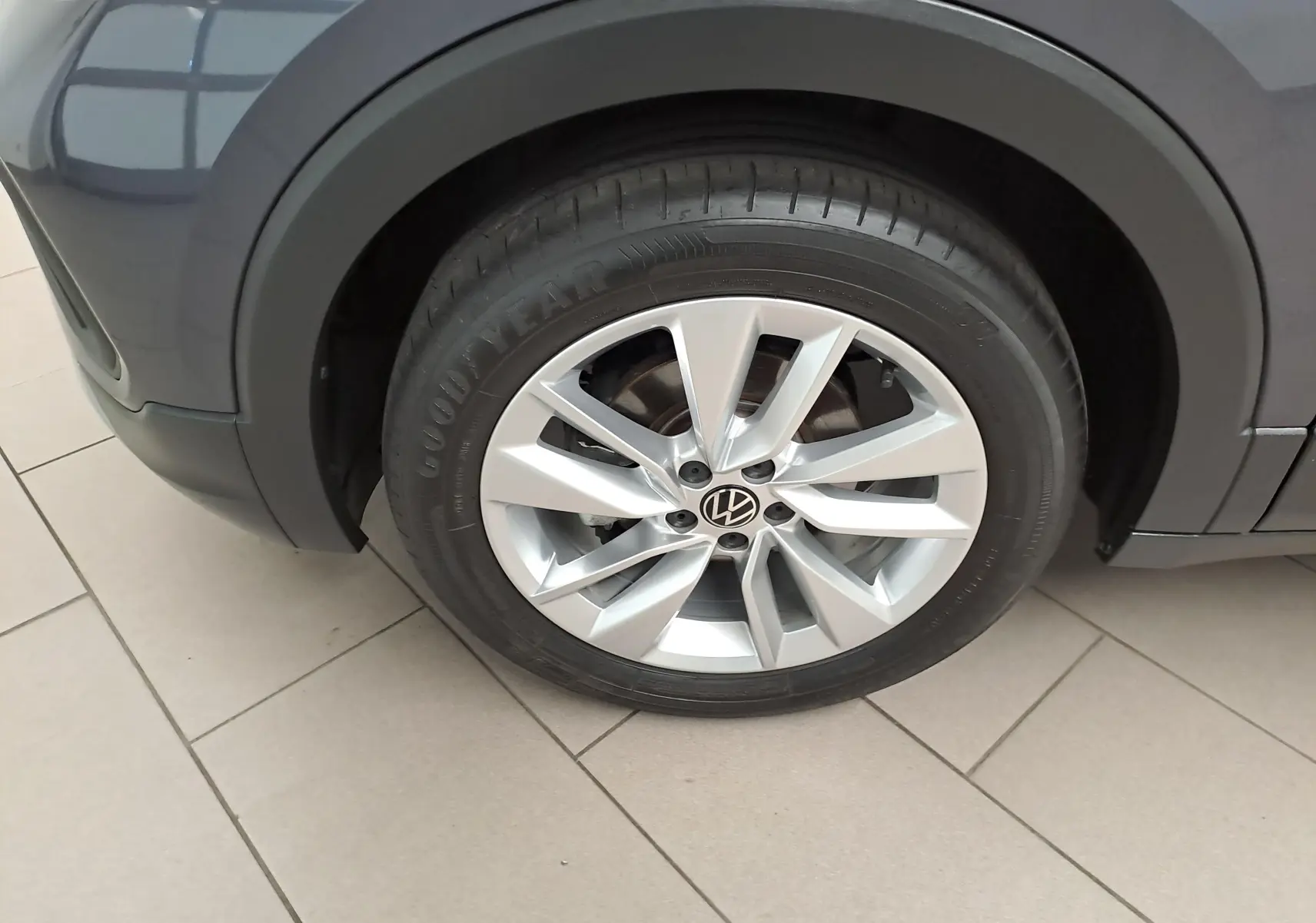 Gros plan sur la roue avant gauche du Volkswagen T-Cross gris cendré avec jante alliage et pneu Goodyear.