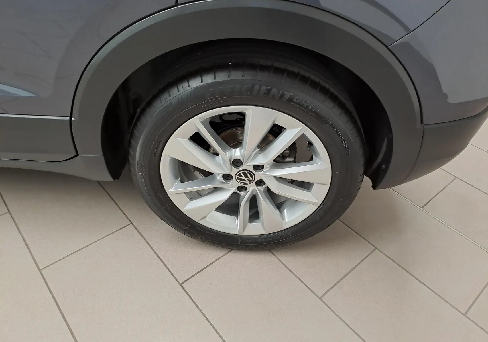 Gros plan sur la roue arrière droite du Volkswagen T-Cross gris cendré avec jante alliage à 5 doubles branches.