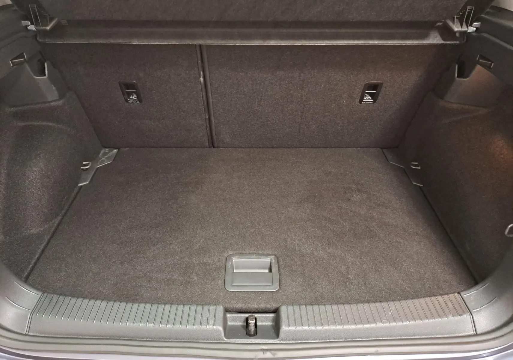 Coffre ouvert du Volkswagen T-Cross gris cendré, vue intérieure montrant un espace de chargement propre et bien agencé.