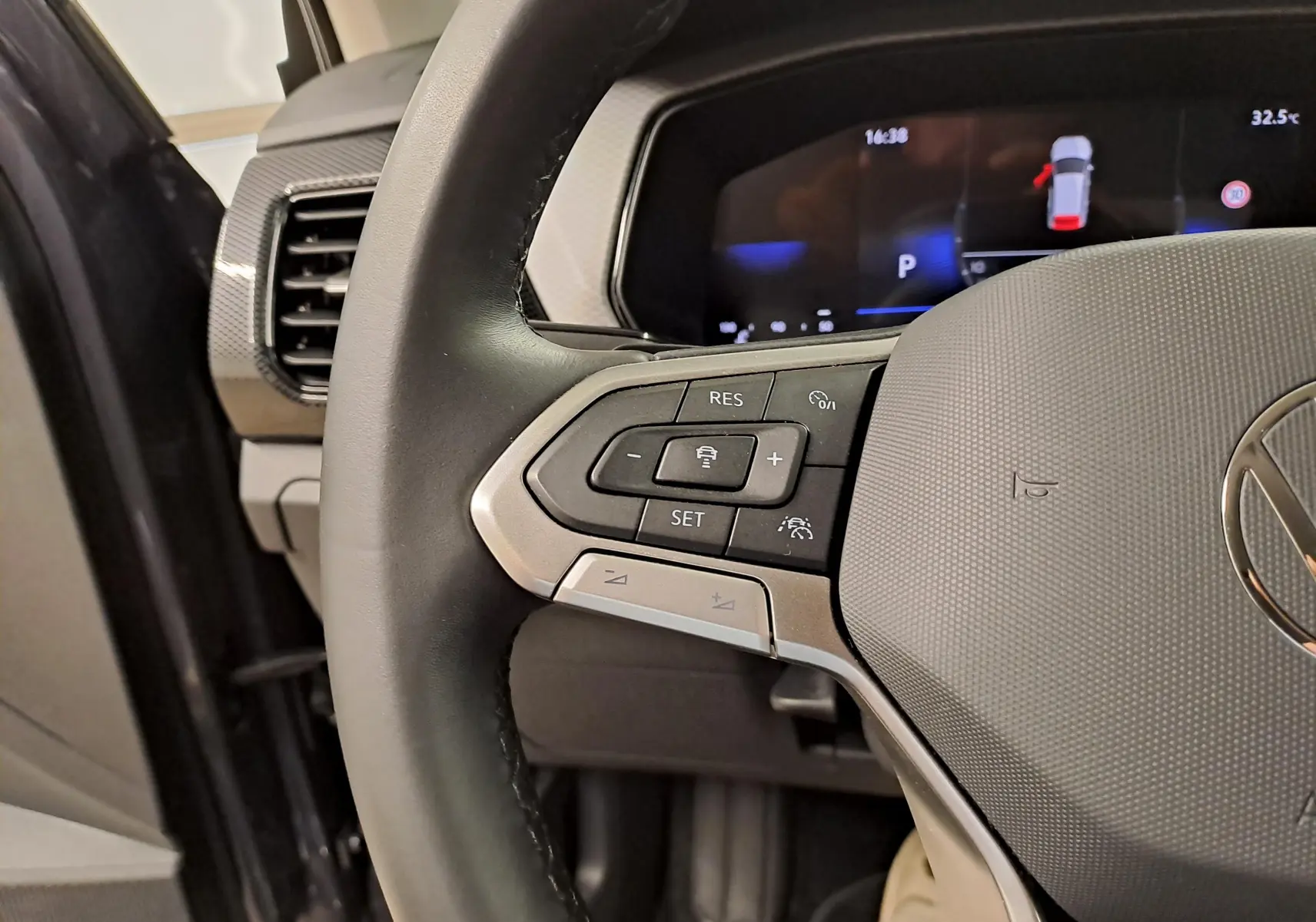 Gros plan sur la partie gauche du volant noir du Volkswagen T-Cross 2025 avec commandes intégrées et tableau de bord numérique.