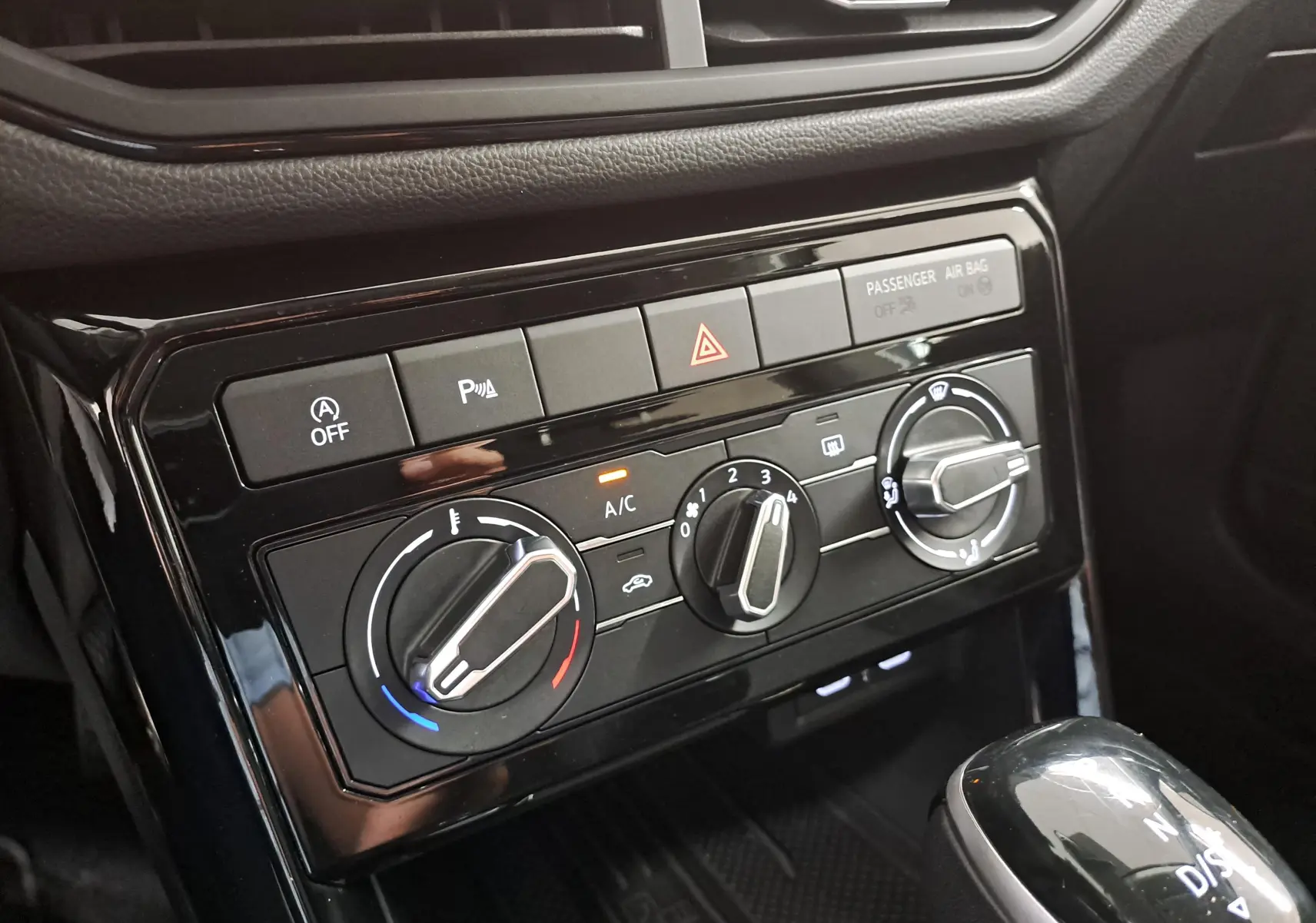 Gros plan sur la console centrale du Volkswagen T-Cross 2025 avec commandes de climatisation et levier de vitesse.