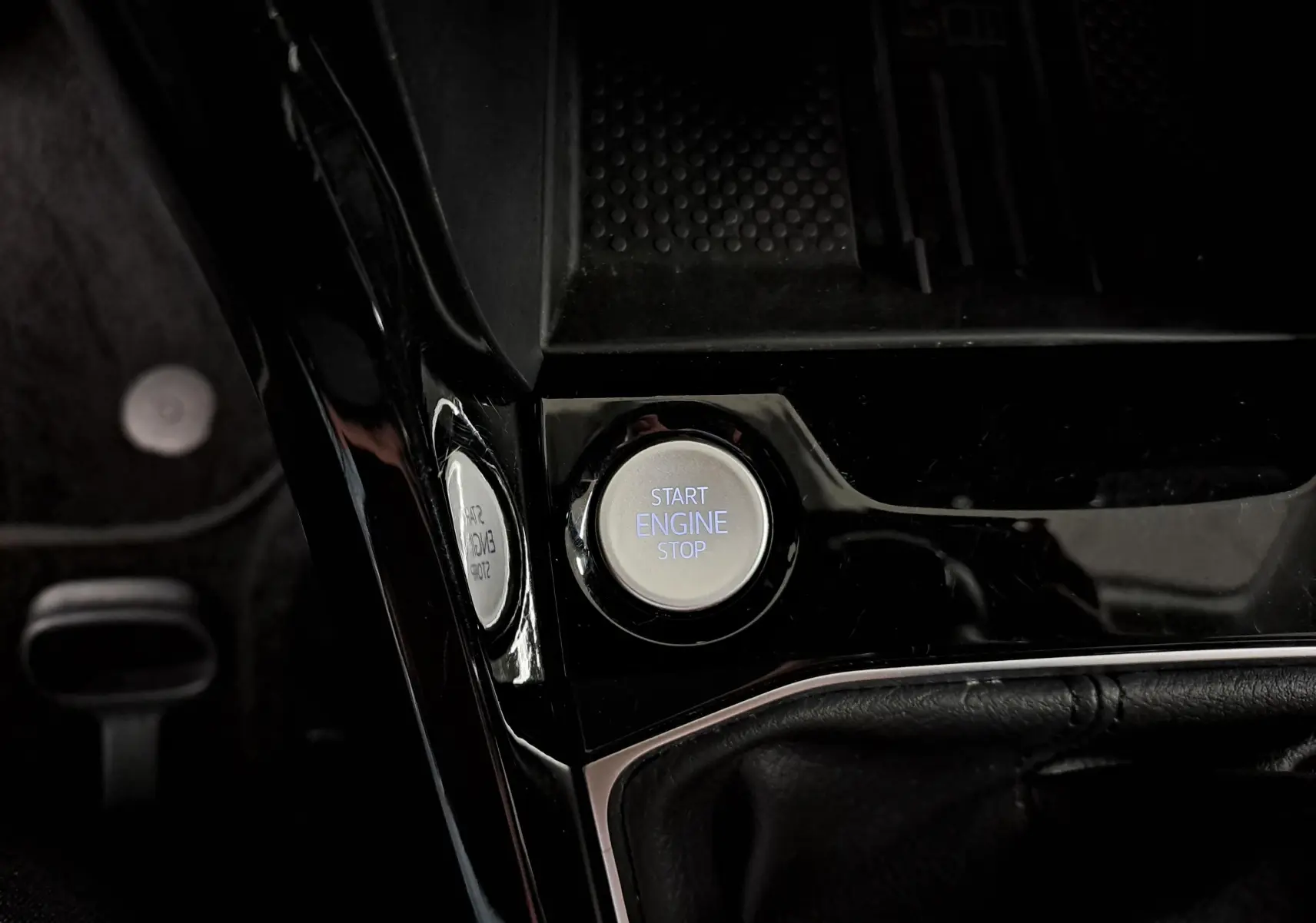 Bouton Start Engine Stop en gros plan sur la console centrale noire d'un Volkswagen T-Cross gris cendré 2025.