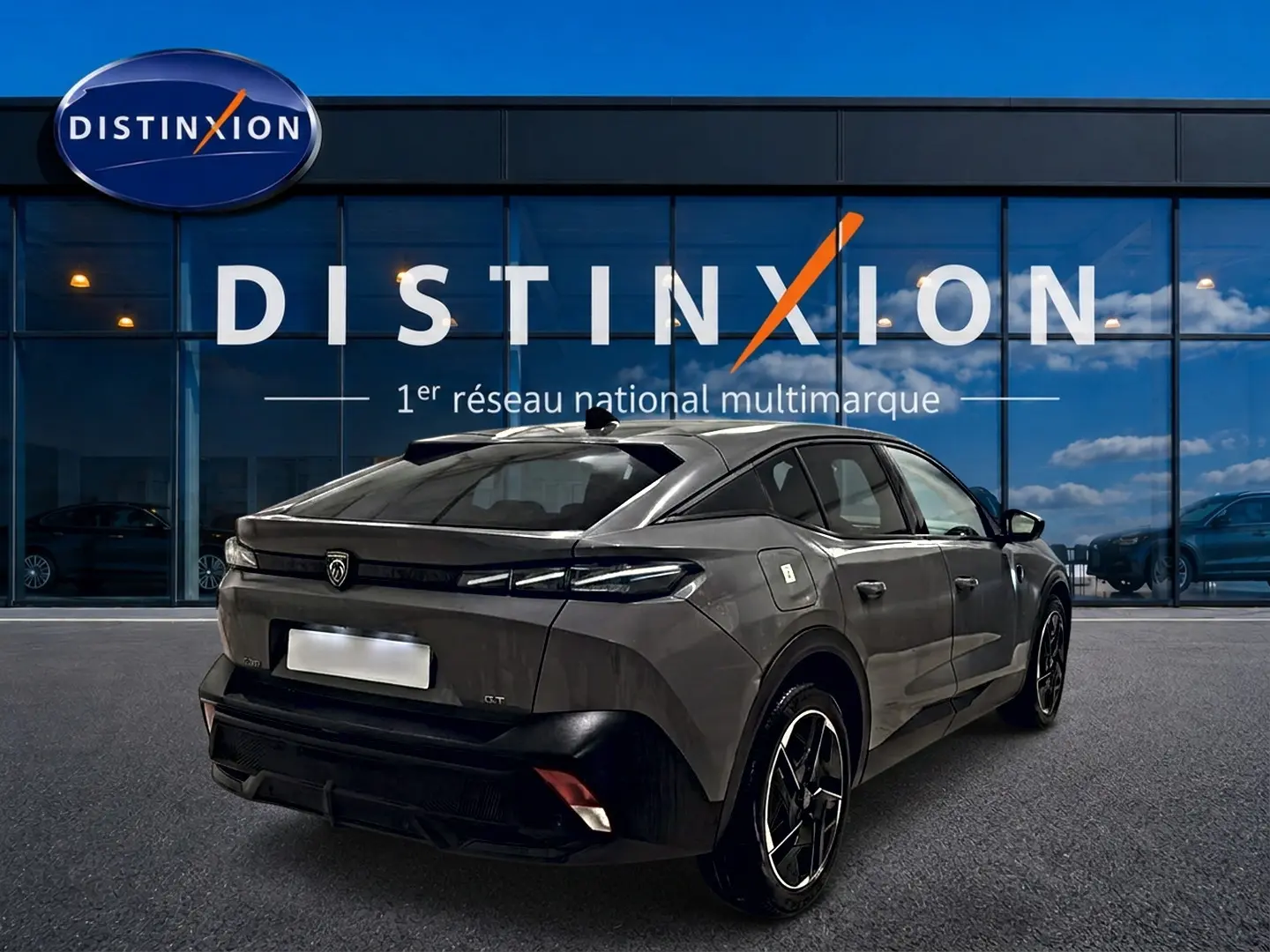 Vue 3/4 arrière droite d'une Peugeot 408 Hybrid 145 GT gris sélénite avec jantes alu noires devant une vitrine Distinxion.
