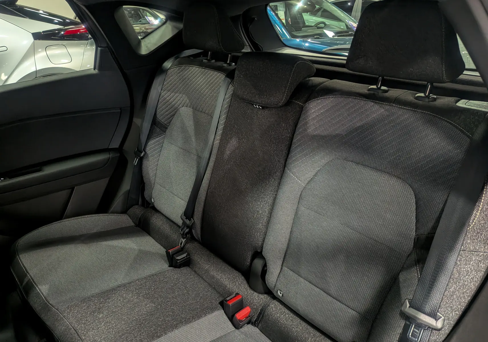 Vue intérieure sur les sièges arrière en tissu gris du Renault Captur 2025, avec ceintures de sécurité et appuie-têtes visibles.