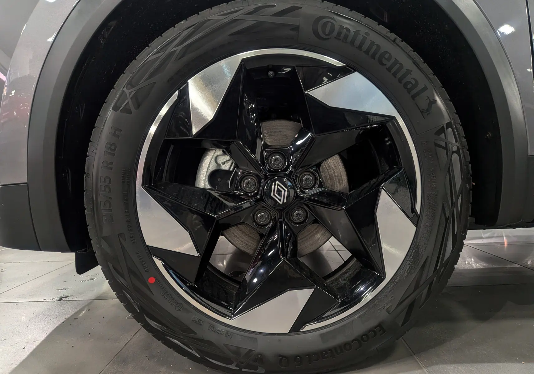 Gros plan sur la roue avant gauche du Renault Captur gris Cassiopé, avec jante noire et argentée au design étoilé.