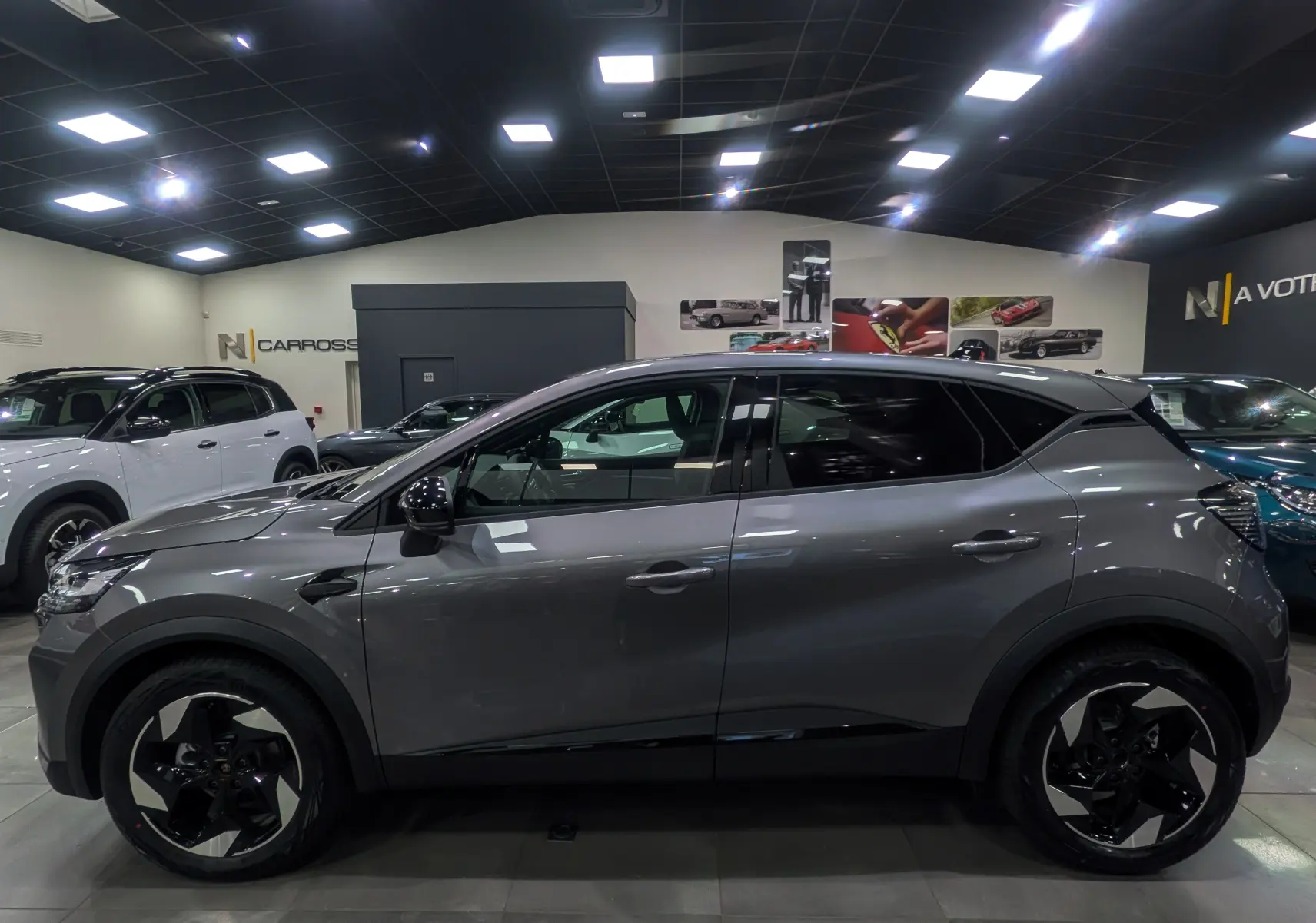 Profil côté gauche du Renault Captur gris Cassiopé 2025 en version Mild Hybrid exposé en showroom lumineux.