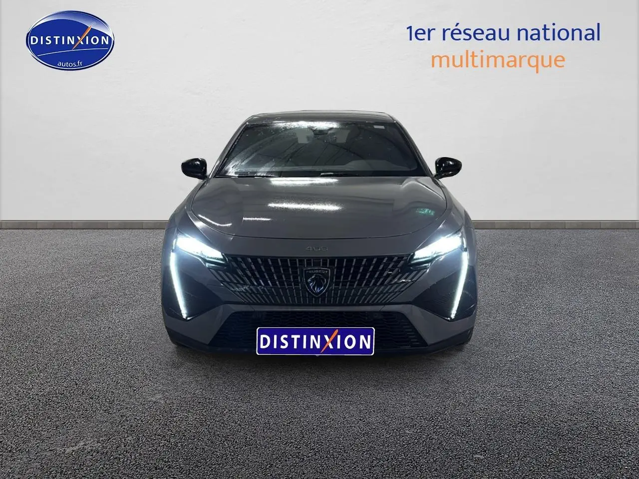 Vue frontale d'une Peugeot 408 Hybrid 145 GT gris sélénite avec phares LED allumés sur fond neutre.