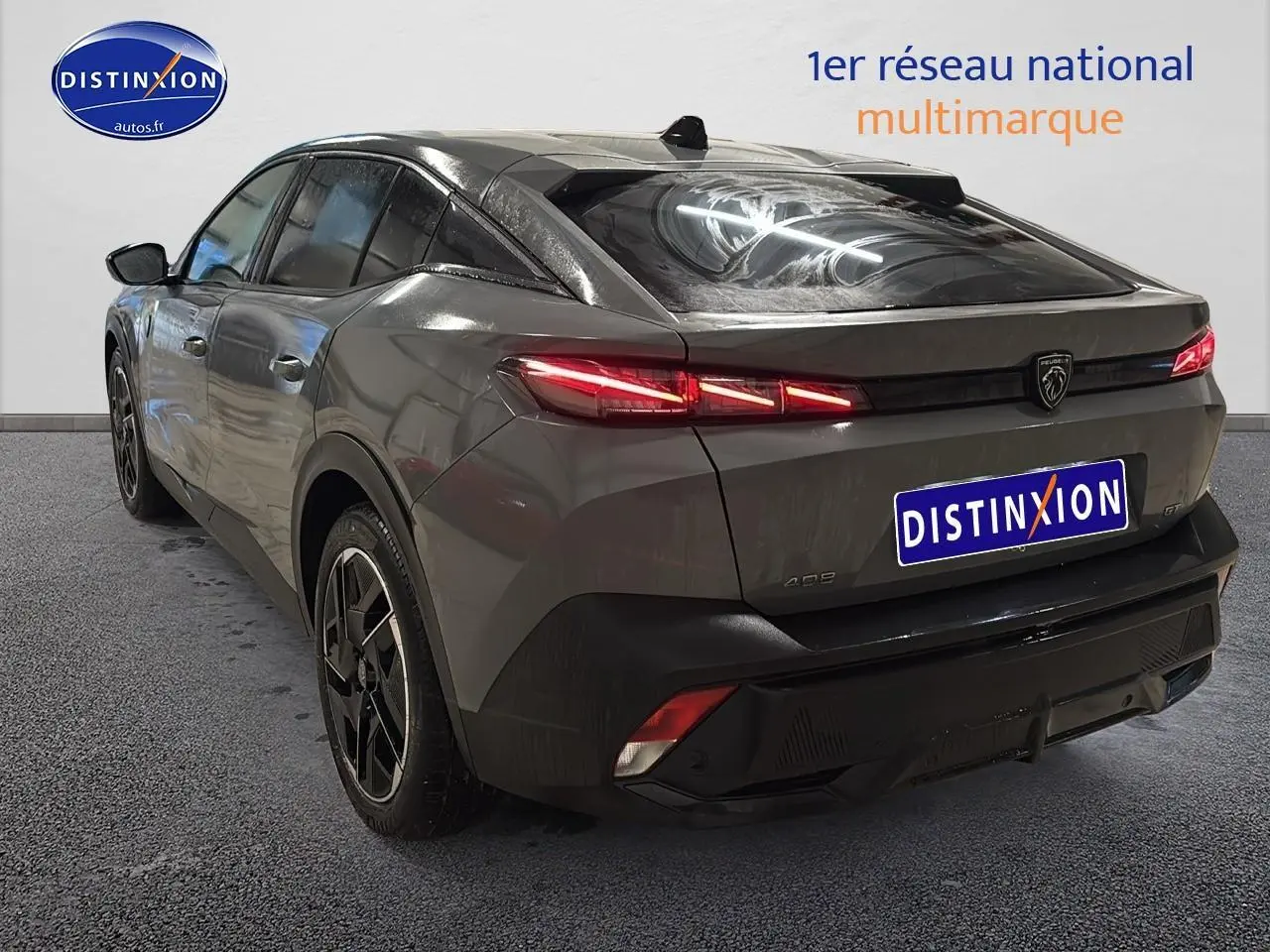 Vue 3/4 arrière droite d'une Peugeot 408 Hybrid 145 GT gris sélénite avec feux arrière LED allumés et jantes alu noires.