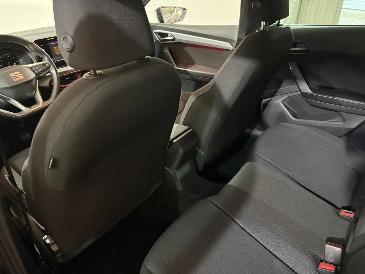 Vue intérieure arrière de la SEAT IBIZA 1.0 TSI 110 FR 2024, sièges tissu noirs et tableau de bord partiel visible.