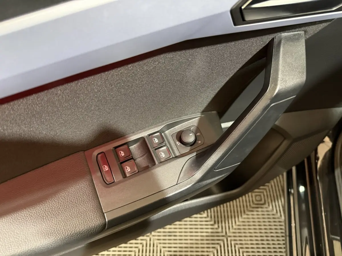 Gros plan sur la commande des vitres et rétroviseurs côté conducteur de la SEAT Ibiza noire 2024.