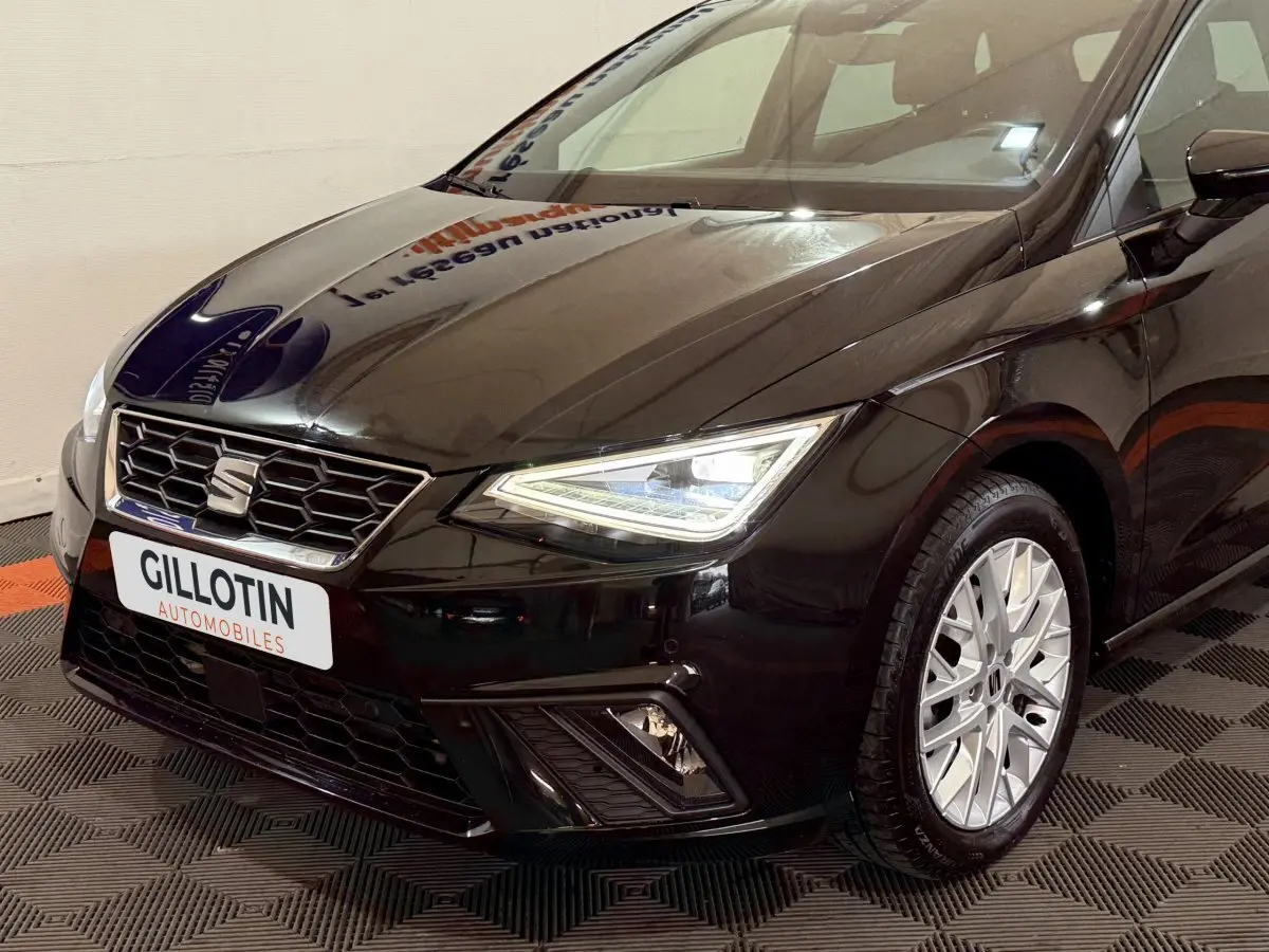 Vue 3/4 avant droite d'une SEAT Ibiza 1.0 TSI 110 FR noire avec phares LED et jantes alu distinctives.