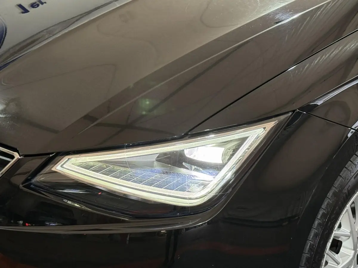 Gros plan sur le phare avant droit LED d’une SEAT Ibiza 1.0 TSI 110 FR noire, avec carrosserie brillante.