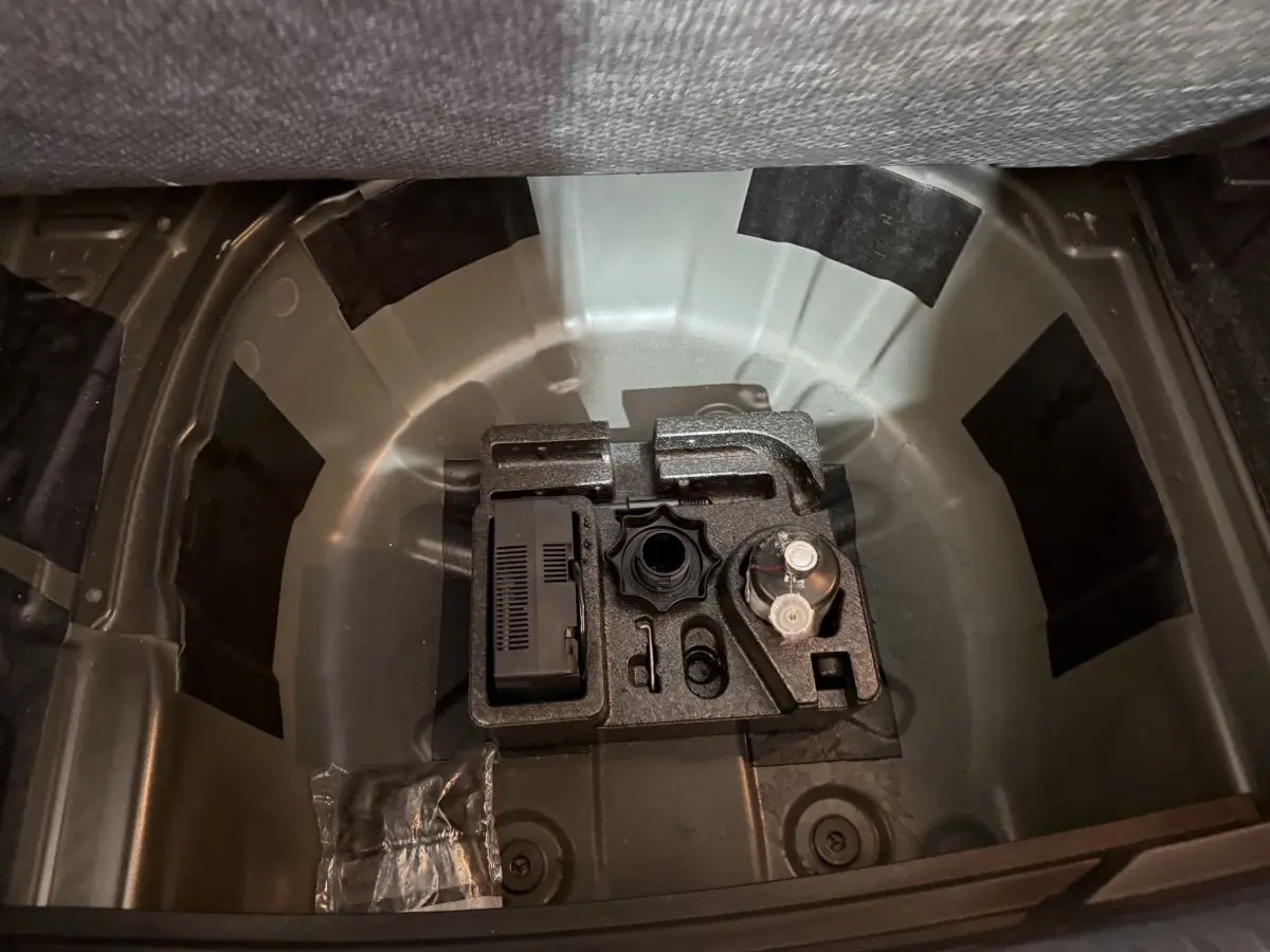 Vue plongeante sur le coffre ouvert d'une SEAT Ibiza noire, montrant le rangement sous la tablette sans roue de secours.