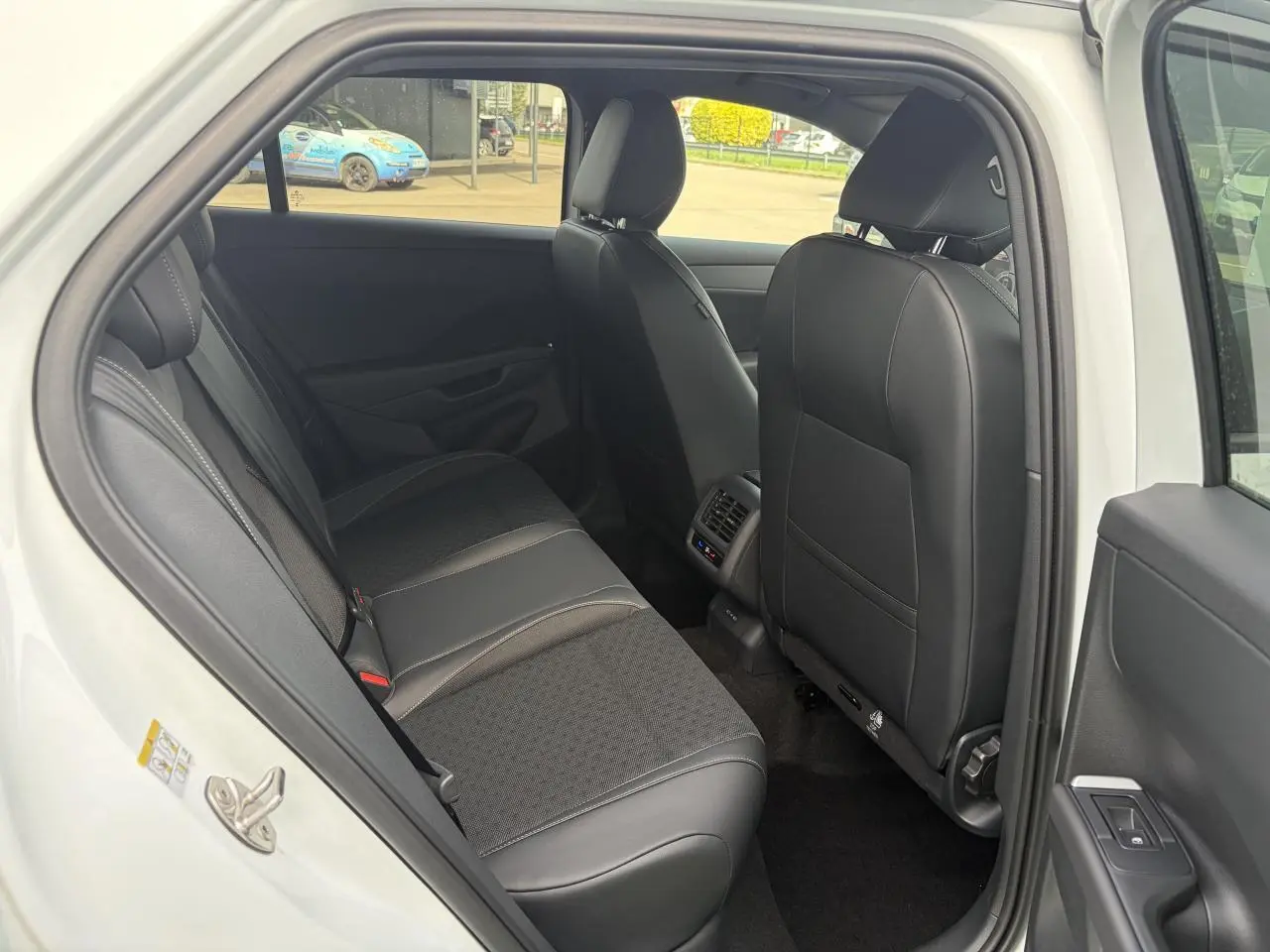 Vue intérieure côté gauche sur la banquette arrière en tissu et cuir noir du Volkswagen T-Roc blanc toit noir 2026.