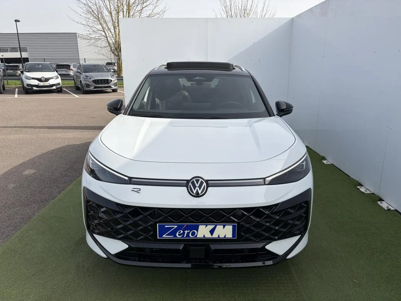 Vue avant d'un Volkswagen T-Roc blanc pur avec toit noir et calandre R-Line noire, sur fond extérieur neutre.