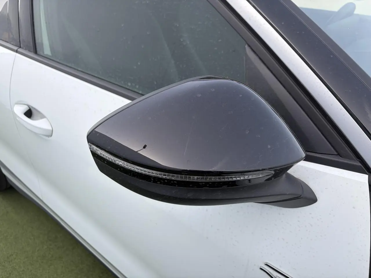 Rétroviseur noir côté gauche en gros plan sur Volkswagen T-Roc blanc pur avec toit noir, vue partielle de la porte avant.