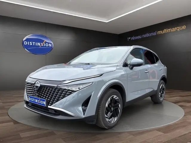 Vue 3/4 avant d’un Nissan Qashqai gris foncé exposé en showroom avec calandre noire et jantes stylisées.