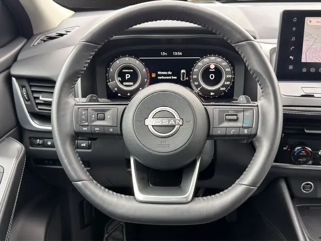 Vue centrée sur le volant cuir du Nissan Qashqai 2025 avec tableau de bord numérique et écran tactile latéral.