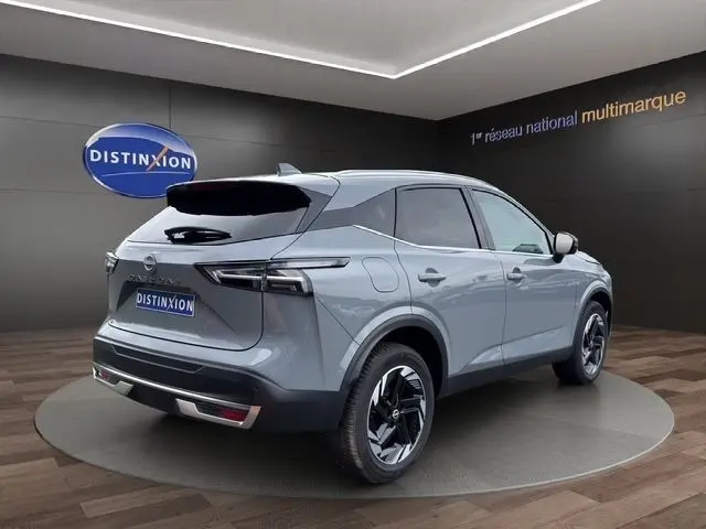 Vue 3/4 arrière droite du Nissan Qashqai gris foncé 2025 avec jantes noires et toit noir dans un showroom.
