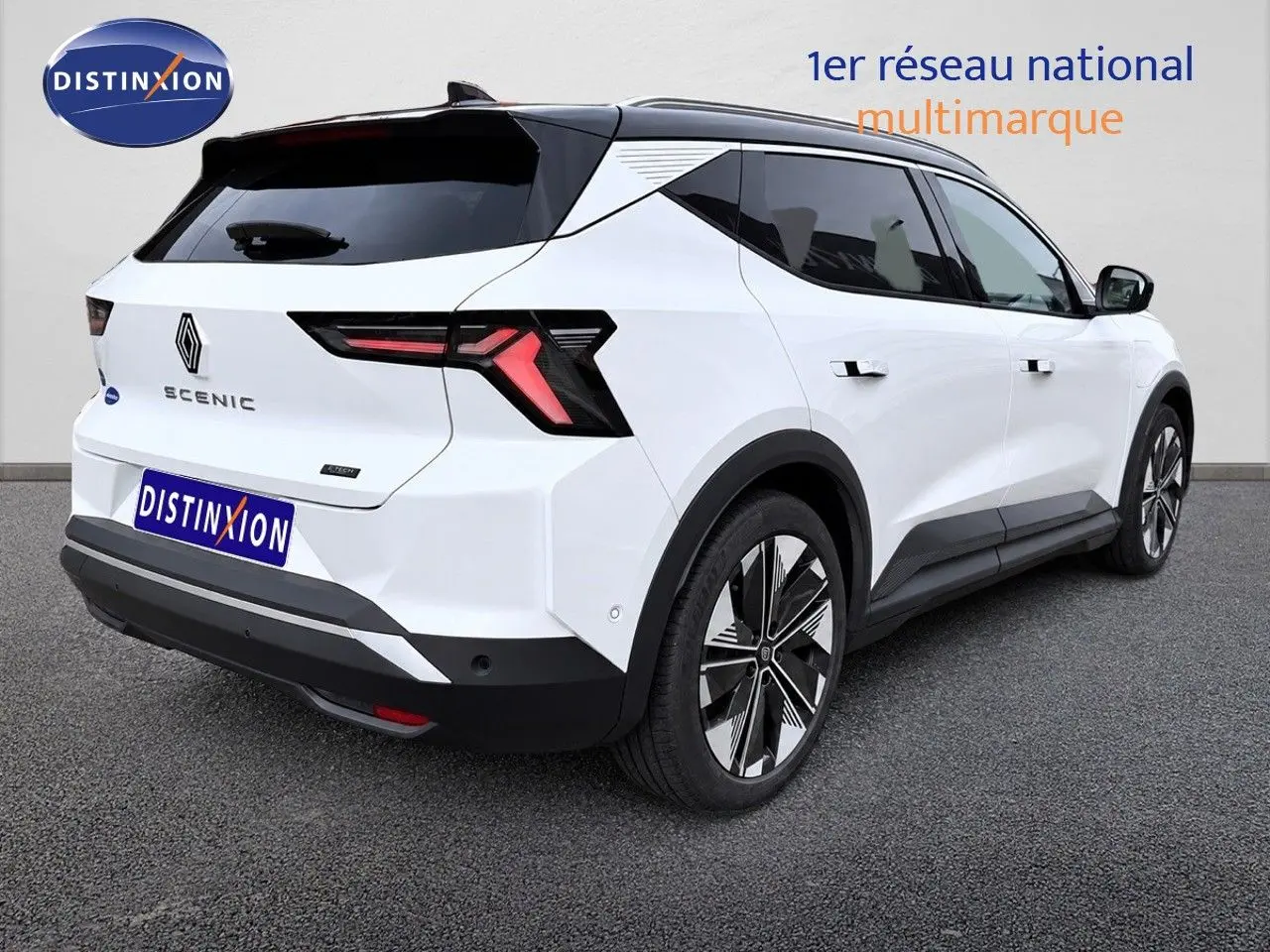 Vue 3/4 arrière droite du Renault Scénic 5 blanc électrique 2024 avec feux arrière en forme de flèche et jantes stylisées.