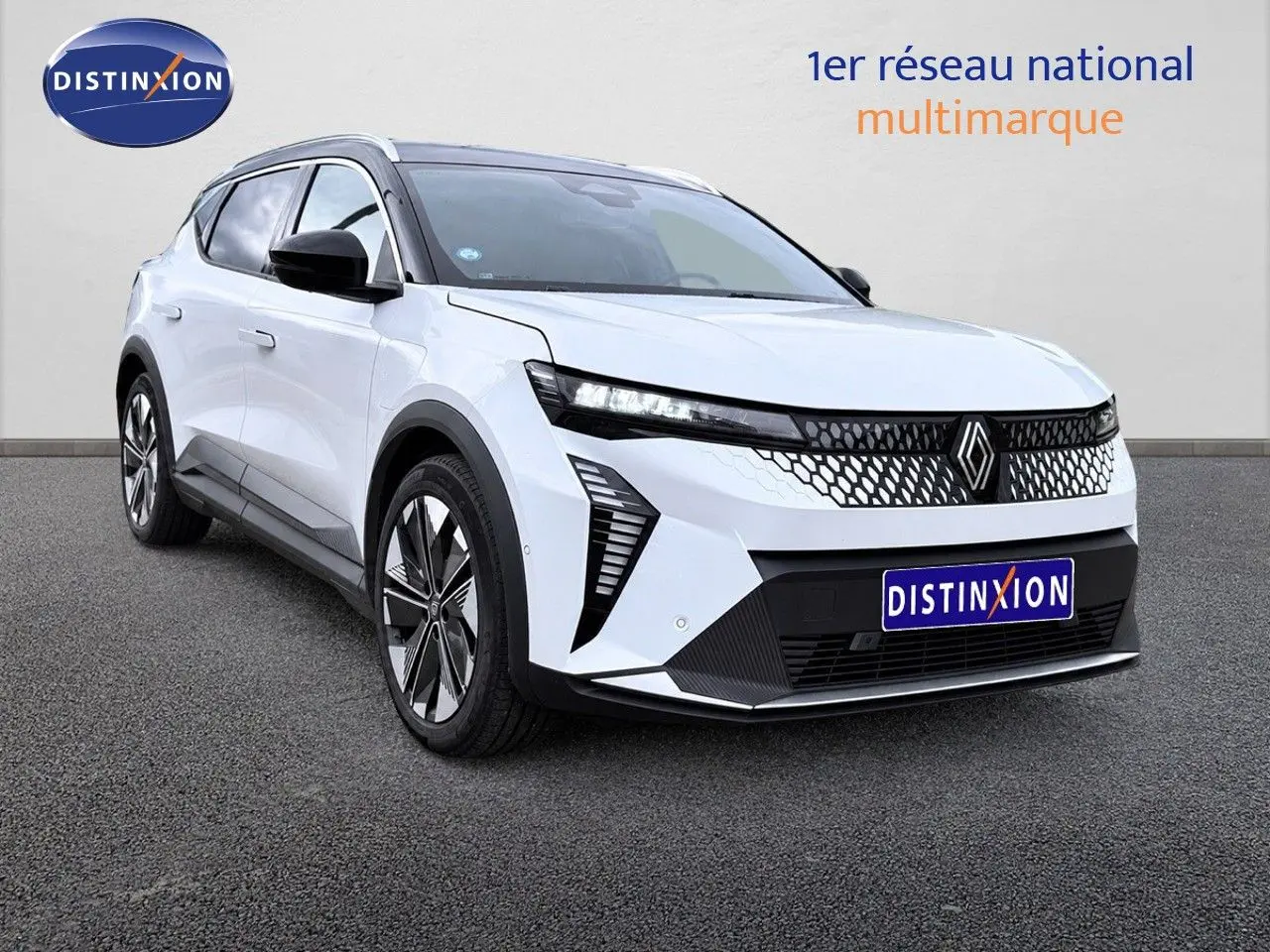 Renault Scénic 5 électrique blanc en 3/4 avant droit, avec calandre à motif nid d'abeille et jantes stylisées.
