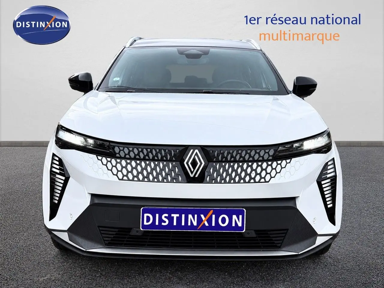 Vue de face du Renault Scénic 5 blanc électrique 2024 avec calandre à motif nid d'abeille et phares fins LED.