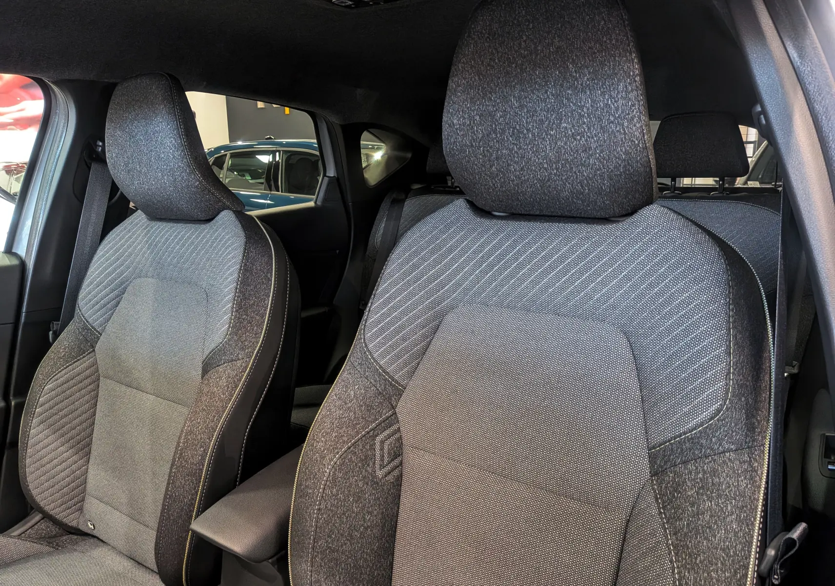 Gros plan sur les sièges avant en tissu gris du Renault Captur Mild Hybrid 160 CH EDC TECHNO 2025, intérieur moderne.