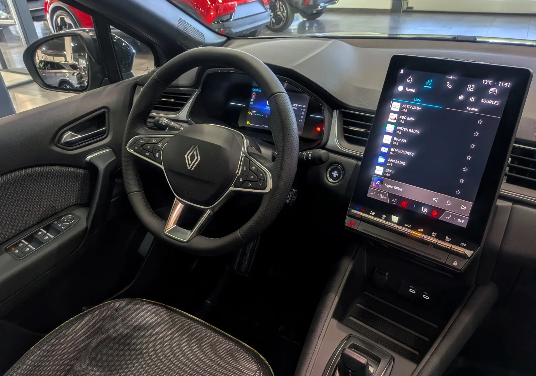 Vue intérieure du tableau de bord du Renault Captur 2025 gris rafale, avec volant multifonction et écran tactile vertical.