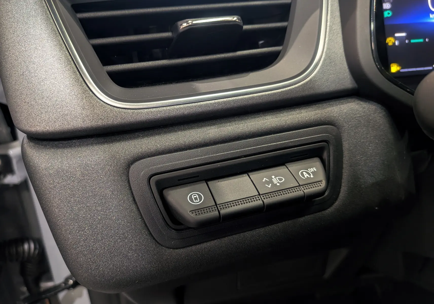 Gros plan sur les commandes de réglage des phares et arrêt auto start du tableau de bord du Renault Captur gris rafale 2025.