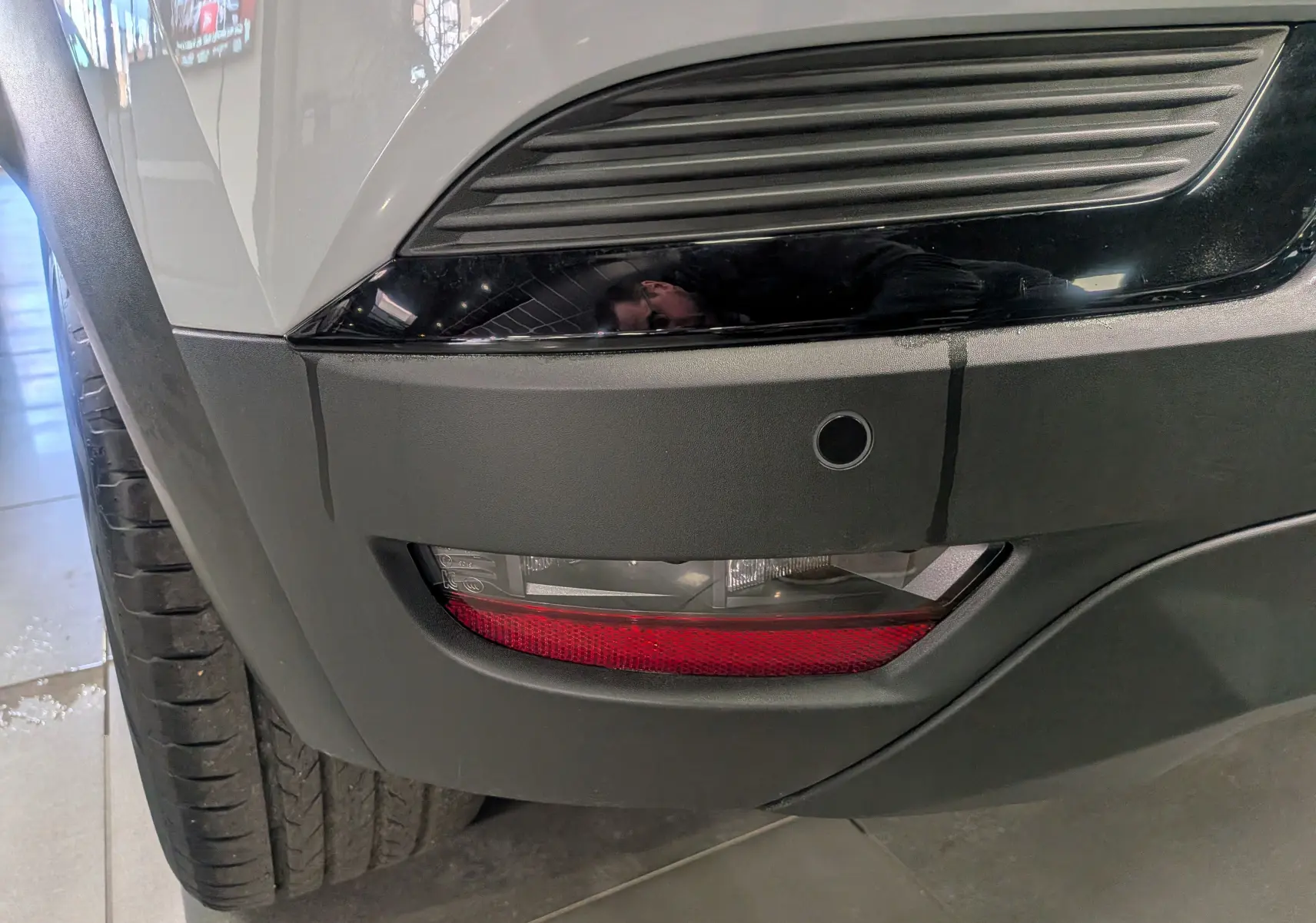 Gros plan sur le pare-chocs avant droit gris rafale du Renault Captur 2025 avec feu antibrouillard et capteur de stationnement.