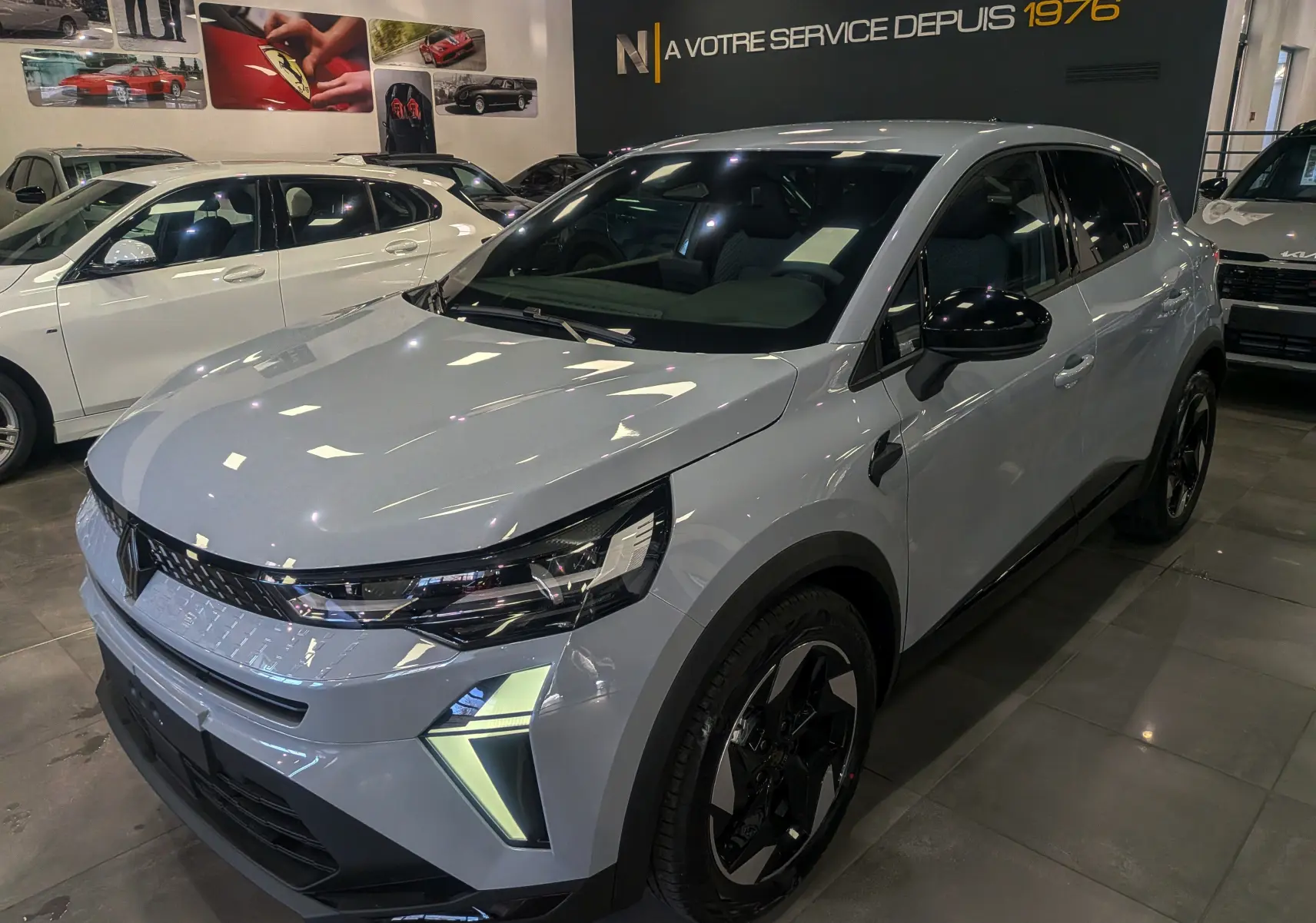 Vue 3/4 avant droite du Renault Captur gris rafale 2025 avec feux LED et jantes noires bicolores en showroom.