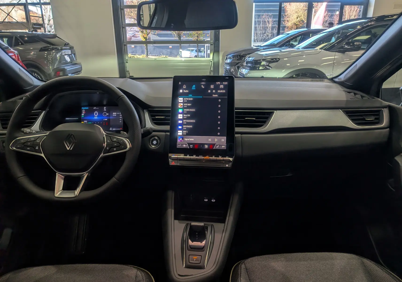 Intérieur du Renault Captur 2025 gris rafale, vue frontale du tableau de bord avec écran tactile vertical et volant multifonction.